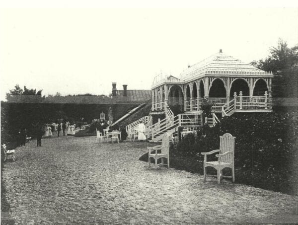 Riviera Café Terrace and Grounds Historic photograph of a wooden pavilion café with terrace, scattered chairs and strolling visitors on a gravel path
