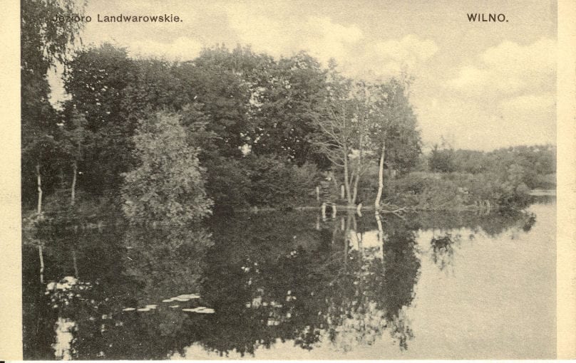 Sepia postcard of a wooded lakeshore with trees mirrored in still water, captioned Landwarowskie lake, Wilno